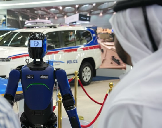 Security robot displayed in front of a police vehicle at a Milipol Qatar exhibition stand