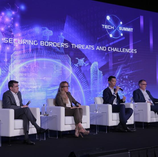 Milipol TechX conference on border security, with international experts speaking on stage.