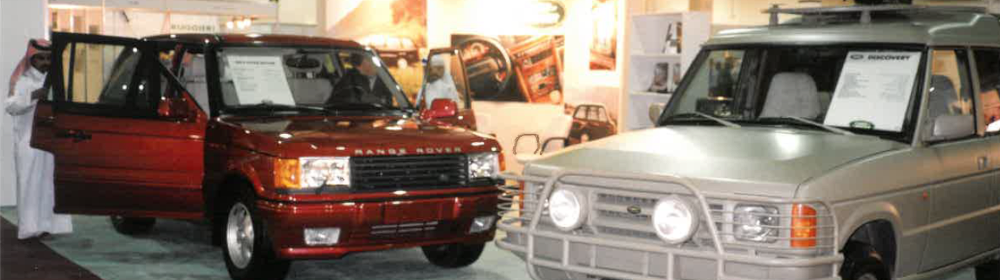 Two Range Rover vehicles displayed inside the Milipol Qatar exhibition hall with participants observing in 1996.
