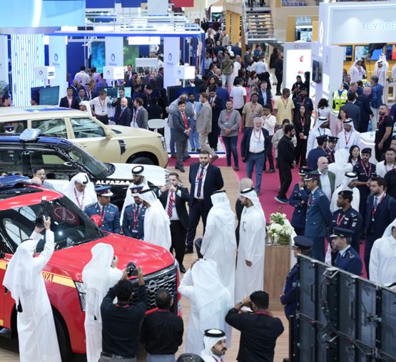 Overview of Milipol Qatar exhibition with a crowd of visitors and security vehicles on display
